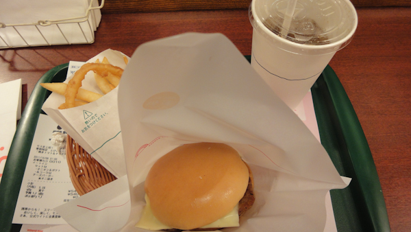 a plain looking cheeseburger, a half and half bag of rings and fries, and a fountain soda on a tray